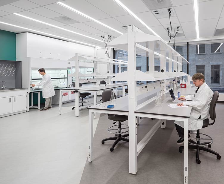 Man sitting at a bench in a lab outfitted with Formaspace furniture.